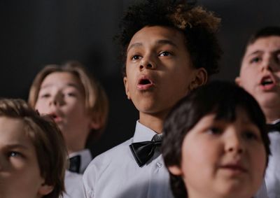 Boys wearing bowties and white shirts singing in a choir.